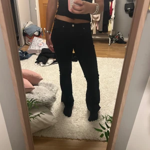 Svarta bootcut jeans från Gina Tricot - Säljer ett par svarta jeans från Gina Tricot med bootcut-modell. Byxorna har hyfsat låg midja, klassisk femficksdesign och dragkedja med knapp framtill. Har klippt av dom där nere och gjort en slits så de är lite kortare än originalet. 