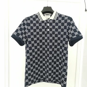Gucci piké - Snygg marinblå pikétröja från Gucci med klassiskt vitt GG-mönster över hela tröjan. Perfekt för dig som vill sticka ut med en lyxig och trendig look. Skriv ifall du undrar något!!