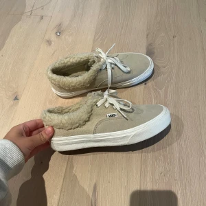 Beige Vans sneakers med foder - Säljer ett par beige Vans sneakers med vit sula och snörning. Skorna har mjukt teddyfoder runt öppningen och insidan, vilket gör dem extra sköna och varma. Ovandelen är i mocka och de har den klassiska Vans-loggan på sidan och bak. I väldigt bra skick. Jag har vanligtvis storlek 38 och dessa är lite små på mig så skulle säga en storlek 37, men det står 36 1/2 i de!😃