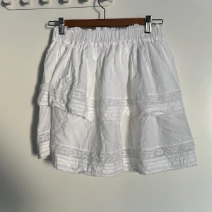 Vit volangkjol från Bik Bok XS - Superfin vit kortkjol från Bik Bok i bomull med bred resår i midjan. Kjolen har flera lager med volanger och spetsdetaljer som ger en romantisk och somrig vibe. Perfekt att styla med en enkel topp eller stickad tröja. Om du köper denna tillsammans med den förra annonsen får du båda för 80kr!