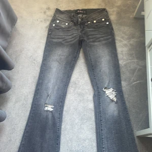 Svarta bootcut jeans G.Rise XS - Coola svarta jeans från G.Rise med bootcut passform och slitna detaljer på benen. Jeansen har rosa kontrastsömmar och klassiska fem fickor. Materialet är jeans och de har snygga nitar och dragkedja framtill. Har sprättat upp de där nere för att de ska bli längre. Innerbens längd är 74 cm Midje mått 30 priset kan diskuteras de säljs inte längre 