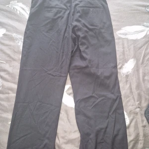 Svarta kostymbyxor med raka ben - Snygga svarta byxor med raka ben. Byxorna har en stilren look och passar perfekt till en dressad outfit. Materialet känns mjukt och följsamt, och midjan är normalhög. Perfekta för dig som gillar en clean och tidlös stil. Byxorna är köpt från Lindex och är i storlek 40 som är ungefär M/L