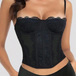 Svart spetskorsett med smala axelband - Säljer en svart korsett med spetsdetaljer. Perfekt att styla med höga jeans eller kjol. Även använda inför fest, halloween 