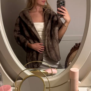 Brun pälsjacka från Glenoit - Säljer en supersnygg brun pälsjacka från Glenoit med bred krage och trekvartsärmar. Jackan har en lyxig känsla och är tillverkad i mjukt pälsmaterial med glansig beige insida. Perfekt för dig som vill sticka ut med en vintagevibe. Ponchon är i äkta päls.