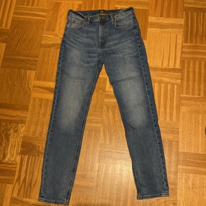Blå jeans från Lee - Snygga blå jeans från Lee med Lee-logga på bakfickan. Jeansen har smal passform, raka ben och normal midja. Storlek: W30 / L32