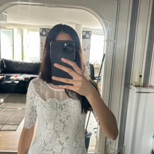 Vit spets topp med halvärmar - Superfin vit top med spetsdetaljer och transparent parti upptill. Halvärmade ärmar och figurnära passform. Perfekt för dig som gillar romantisk och feminin stil. Toppen har vacker spets över hela och rund halsringning.