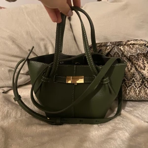 Grön handväska med gulddetalj - Den populära väskan från Lindex i mörkgrön med guldiga detaljer💗💗🙌  Köpt för någon månad sen men knappt använd🥰 
