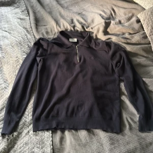 Mörkblå långärmad tröja med dragkedja - Mörkblå långärmad tröja från Lundbergh med skjortkrage och en snygg half zip-dragkedja framtill. Perfekt för lager-på-lager och har en stilren look med diskret logga på bröstet. Skön och mjuk känsla, passar till många outfits. Önskas mer bilder medela 