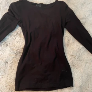 Svart långärmad tröja Gina Tricot - En svart långärmad tröja från Gina Tricot i figurnära modell. Tröjan har rund halsringning och är tillverkad i mjuk bomullsmix, perfekt för lager-på-lager eller som enkel bas i garderoben. Armarna har slits