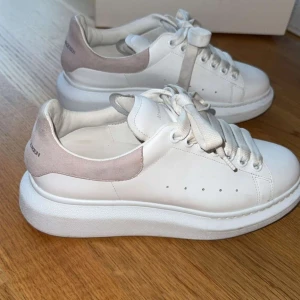 Alexander McQueen - Säljer ett par ikoniska vita sneakers från Alexander McQueen med chunky sula och breda snören. Skorna har detaljer i ljusbeige mocka på hälen och är tillverkade i skinn. I storlek 37.