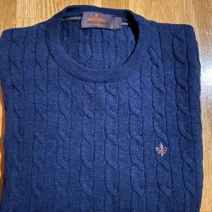 Marinblå kabelstickad tröja Morris - Kabelstickad marinblå tröja från Morris i 100% merinoull. Säljer för att jag har växt ur den. Mycket bra skick då den inte har några defekter.Storlek S.