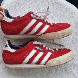 Röda Adidas Gazelle sneakers mocka - Säljer ett par retro Adidas Samba sneakers i röd mocka med vita. Storlek 42 2/3 men har själv strl 39 och passar så de är små i storleken. Fint skick!!
