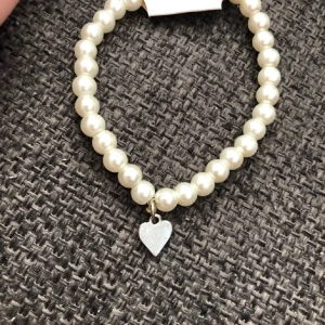 Pärlarmband med hjärtberlock - Gulligt armband med vita pärlor och ett litet silver hjärthänge som är äkta silver. 