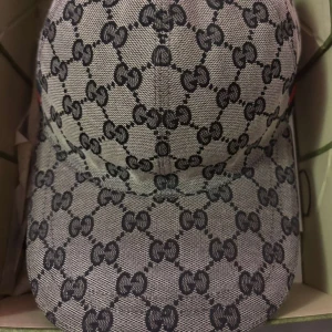 Gucci keps  - Snygg keps från Gucci med klassiskt GG-monogram i svart på grå bakgrund. Kvitto inklusive box finns med.