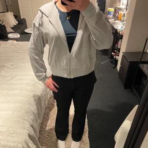 Grå zip hoodie med huva - Säljer en ljusgrå hoodie med dragkedja och huva. Jackan har en croppad passform, långa ärmar och ribbade muddar vid ärmslut och nederkant. Perfekt för chill dagar och enkel att matcha med olika outfits.