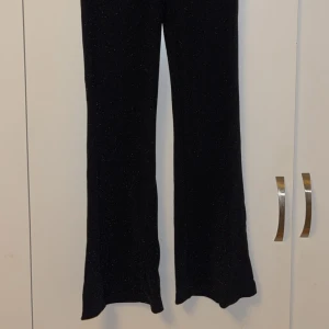 Svarta glittriga bootcut-byxor JDY - Svarta glittriga bootcut-byxor från JDY i ett skönt och stretchigt material. Aldrig använda som nya💕. Innerbenslängden är 77 cm, och den är stretchig i midjan. 