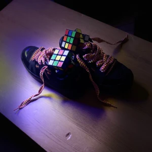 Svarta sneakers Naked Wolfe - Svarta chunky sneakers från Naked Wolfe med coola orange detaljer och breda, färgglada snören i rött, vitt och gult. Skorna har rund tå, platt sula och synliga sömmar. Perfekta för dig som vill sticka ut med din streetstyle.