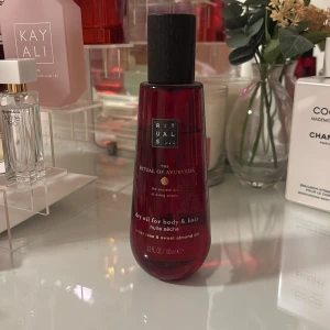 Rituals The Ritual dry oil, body and hair - Röd flaska med torr olja för kropp och hår från Rituals, The Ritual of Ayurveda. Innehåller indisk ros och sötmandelolja. Lyxig och väldoftande olja som ger glow och mjuk känsla. Kommer i en elegant plastflaska med svart kork.