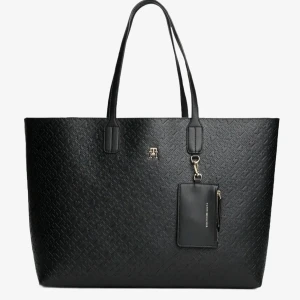 Svart shoppingväska från Tommy Hilfiger - Stilren svart shoppingväska från Tommy Hilfiger med präglat mönster och guldfärgad logga. Väskan har dubbla handtag och en avtagbar liten plånbok med dragkedja. Helt oanvänd, köpte med ett köp och sen åkt utomlands så retur gälldes ej när jag väl kom hem.