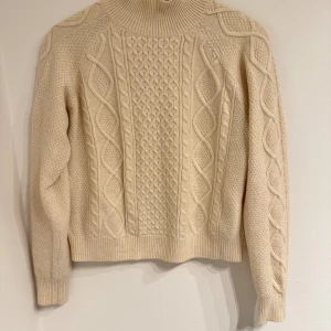 Beige tröja med flätmönster Primark - Säljer en beige polotröja från Primark i storlek S. Tröjan har ett snyggt flätmönster på framsidan och är stickad med grov struktur. Hög krage och långa ärmar ger en chill och varm vibe. Perfekt för dig som gillar klassisk stil med twist.