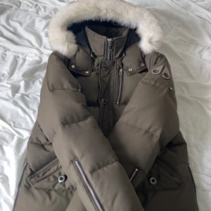 Moose Knuckles dunjacka med päls - Snygg mörkgrön dunjacka från Moose Knuckles med fluffig vit päls på huvan. Jackan är såklart ÄKTA. Skriv vid minsta lill fråga. Kan mötas i Stockholm 