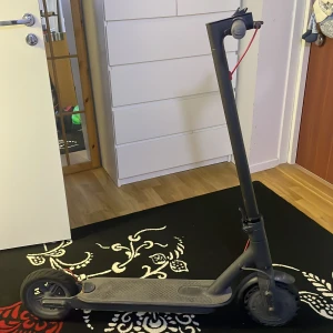 Xiaomi Mi Electric Scooter - Snygg Xiaomi Mi elscooter i svart, med tydlig LED-display och vikbar design. Batteriindikatorn visar laddning, och scootern är i gott skick med endast lättare smuts på fotplattan. Perfekt för smidig pendling och stadskörning.