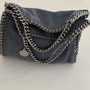 Stella McCartney väska tiny - Säljer min stella McCartney väska i minsta storleken, tiny. Det är den blåa färgen men 3e bilden är bara för att visa modellen. Äktehetsbevis finns. Priset går att diskutera 💕 hör av dig vid frågor eller intresse🫶🏼🫰🏼det går att köpa direkt men skriv till mig först för vill ha kontakt med köparen innan jag skickar väskan🥰