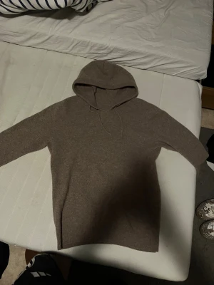 Beige hoodie i kashmir med huva - Mjuk och stilren beige hoodie i kashmir med huva och snörning. Tröjan har långärmade och en stilren look som gör den extra skön. Perfekt för dig som gillar minimalistisk look och vill ha något riktigt comfy.