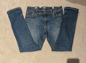 Blå slim jeans från Jack & Jones - Snygga blå jeans från Jack & Jones, modell Glenn Slim. Klassisk femficksdesign med dragkedja och knapp framtill. Jeansen har en slim passform och är tillverkade i mjukt denimtyg.