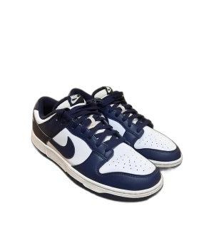Nike Dunk Low vit/marinblå sneakers - Nike Dunk Low sneakers i vit och marinblå färg med klassisk swoosh på sidan. Skorna har snörning, rund tå och platt sula. Ovandelen är i skinn och textil, med perforeringar på tån för extra ventilation. Perfekt för dig som gillar retrostil och streetwear.