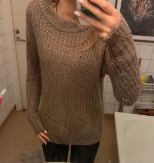 Beige stickad tröja med grov struktur - Säljer en beige stickad tröja med grov struktur och rund halsringning. Tröjan har lång ärm och en avslappnad passform, perfekt för lager på lager under kyliga dagar. Enkel och stilren design som funkar till det mesta.