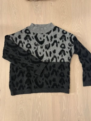 Cool stickad tröja  - Snygg stickad tröja från Mango i grått och svart med leopardmönster. Tröjan har ribbad hög hals och långa ärmar. 