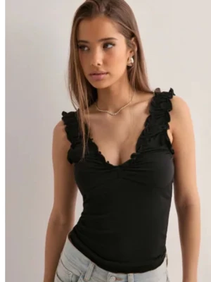 Svart volanglinne med djup v-ringning - Säljer ett svart linne med volangdetaljer längs axelbanden och djup v-ringning. Ny utan prislapp och helt slutsåld.