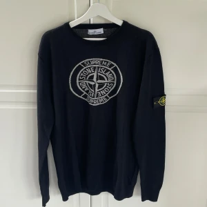 Svart stickad Stone Island  - Säljer en svart stickad tröja från Stone Island. Tröjan har ett stort broderat logomärke på bröstet och klassisk Stone Island-patch på ärmen. Rund hals och långa ärmar. Perfekt för dig som gillar streetwear.