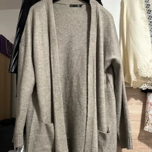 Beige lång kofta med fickor - Mysig och lång beige kofta från Lager 157 med öppet framtill och två praktiska fickor. Koftan har ribbade muddar vid ärmslut och nederkant, vilket ger en chill och avslappnad vibe. Perfekt att slänga på sig när det är lite kyligt ute. Använd engång.