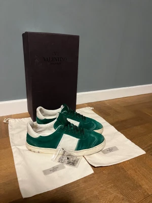Valentino flycrews - Säljer ett par snygga Valentino flycrews sneakers i grön mocka med vita skinnpaneler och vita sulor. Klassisk låg modell med snörning och diskreta nitar på hälen. Perfekta för dig som vill sticka ut med stil. Storlek 42 sitter som 42~43, Sjukt feta, passar till det mesta och är allmänt fräscha skor, skulle säga att skicket är väldigt bra men man bedömer de självklart själv utefter bilderna! Skriv vid minsta fundering🌟