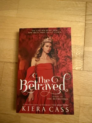 The Betrayed by Kiera Cass English - En spännande och romantisk uppföljare till The Betrothed, där Hollis kämpar med hjärtesorg, intriger och lojalitet. Perfekt för dig som gillar dramatiska berättelser, kungligheter och starka känslor. Passar unga vuxna som vill försvinna in i en värld av kärlek och maktkamp.