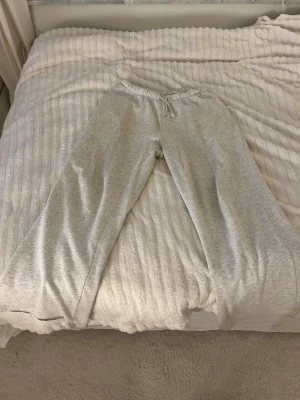 Grå mjukisbyxor från H&M Basic - Säljer ett par ljusgrå mjukisbyxor från H&M Basic i storlek S. Byxorna har elastisk midja med snörning. De har en loose passform och kan vara lite slitna.