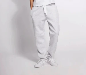 Grå mjukisbyxor med snörning - Snygga ljusgrå mjukisbyxor med snörning i midjan och avslappnad passform. Byxorna har ribbade muddar vid bensluten och praktiska sidofickor. Perfekta för chill dagar eller träning. Matcha med sneakers för en clean look.