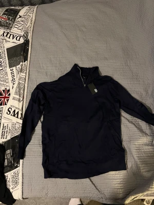 Marinblå half zip polotröja lager 157 - Snygg marinblå polotröja från lager 157 med half zip-dragkedja i halsen. Tröjan har långärmad design och ribbade muddar vid ärmslut och nederkant. Perfekt för dig som gillar stilren och enkel look med lite sportig touch.