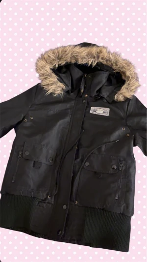 Jacka - Superfin svart Vero Moda-jacka i storlek L! Den är riktigt varm och perfekt för kyliga dagar, med mjuk o skön päls på luvan. Luvan har dessutom en smart zip-up, så du kan ta av luvan om du vill. Fickorna är praktiska, vilket gör jackan lika funktionell som snygg. Passar perfekt för både vardag och lite finare tillfällen. Hör gärna av dig om du vill veta mått eller har några frågor!