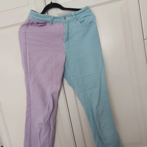 Pastellfärgade jeans med hjärtan - ⚠️ Skriv till mig innan köp ⚠️Unika jeans i tvådelad design med ena sidan ljuslila och andra sidan ljusblå. Baktill finns hjärtformade fickor i kontrasterande färger. Klassisk femficksmodell med knapp och dragkedja. Perfekt för dig som vill sticka ut med färg och coola detaljer.