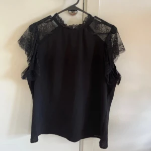 Svart blus med spets - En svart tröja med spets vid ärmar och hals. Toppen är i strl L (passar som M oxå) och kommer från Only. Mycket bra skick och knappt använd!