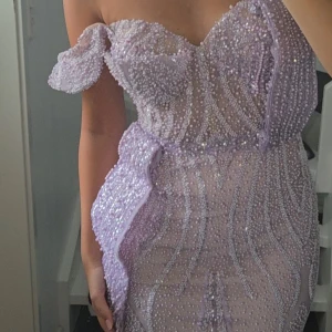 Långklänning balklänning festklänning violett lila pärlor - En långklänning, lämplig som balklänning eller festklänning, i en violett eller lila nyans, dekorerad med pärlor, vilket ger ett magiskt intryck, och kan även fungera som en bröllopsklänning. Använd endast 1 kväll 