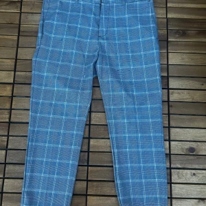 Blå-rutiga skinny kostymbyxor - Snygga blå kostymbyxor med rutigt mönster och skinny fit. Byxorna har klassisk passform med bälteshällor och dragkedja. Perfekta för dig som vill sticka ut med stilrena detaljer och modern look.