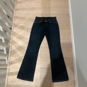 Levis low rise bootcut jeans - Säljer ett par helt nya Levi’s Bootcut Super Low-Waisted jeans i mörkblå färg i modellen 529. De är aldrig använda och lappen finns kvar, även om den är avklippt då jag trodde att jag skulle behålla dem. Jeansen är i storlek 26x32 och passar bäst för någon med storlek XS eller en XXS, eftersom de är i 100% bomull och helt utan stretch. Midjan slutar vid höfterna och mäter 34,5 cm där. Perfekta för dig som gillar en klassisk bootcut-stil med superlåg midja. Hör av dig vid intresse! Jag är 168cm