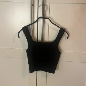 Svart croppad linnetopp från H&M - Säljer en svart croppad linnetopp från H&M i storlek XS. Toppen har breda axelband och fyrkantig halsringning, vilket ger en clean och stilren look. Perfekt att matcha med jeans eller kjol för en enkel och snygg outfit.