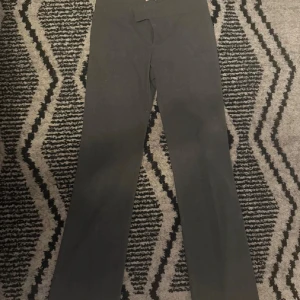 Svarta bootcut byxor från Nelly - Svarta bootcut byxor från Nelly i stretchigt material. Byxorna har hög midja och en enkel, stilren design utan synliga fickor eller detaljer. Perfekta för dig som gillar en klassisk och bekväm look.