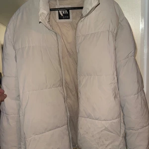 Beige pufferjacka från Zara - Säljer en beige pufferjacka från Zara med hög krage och dragkedja framtill. Jackan har ett quiltat mönster och är tillverkad i syntetmaterial. Perfekt för kalla dagar och har en clean, oversized look.  Den är smutsig så behöver tvättas annars fin!