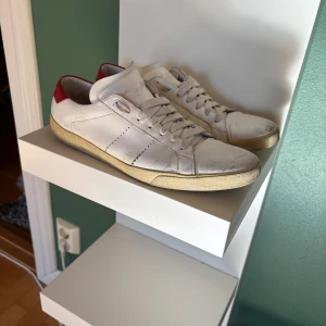 Saint Laurent skor - Snygga vita skor från Saint Laurent med klassisk design och röd detalj på hälen. Skorna är lite slitna därav priset. 